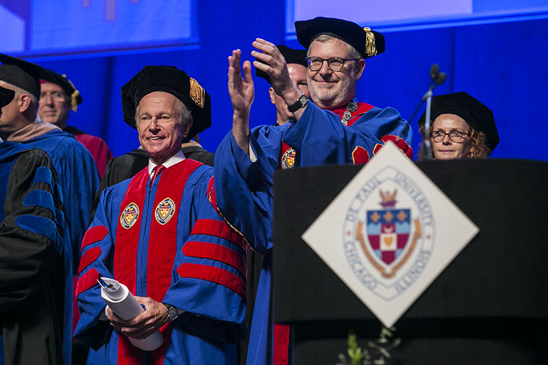 Rick Kash, left, vice chairman of the global consumer information analytics firm Nielsen, and the Rev. Dennis H. Holtschneider, C.M., president of DePaul University, applaud the graduates.